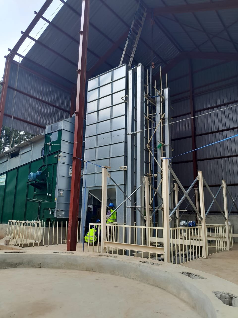 Engineers supervising installation of a grain silo structure inside a warehouse